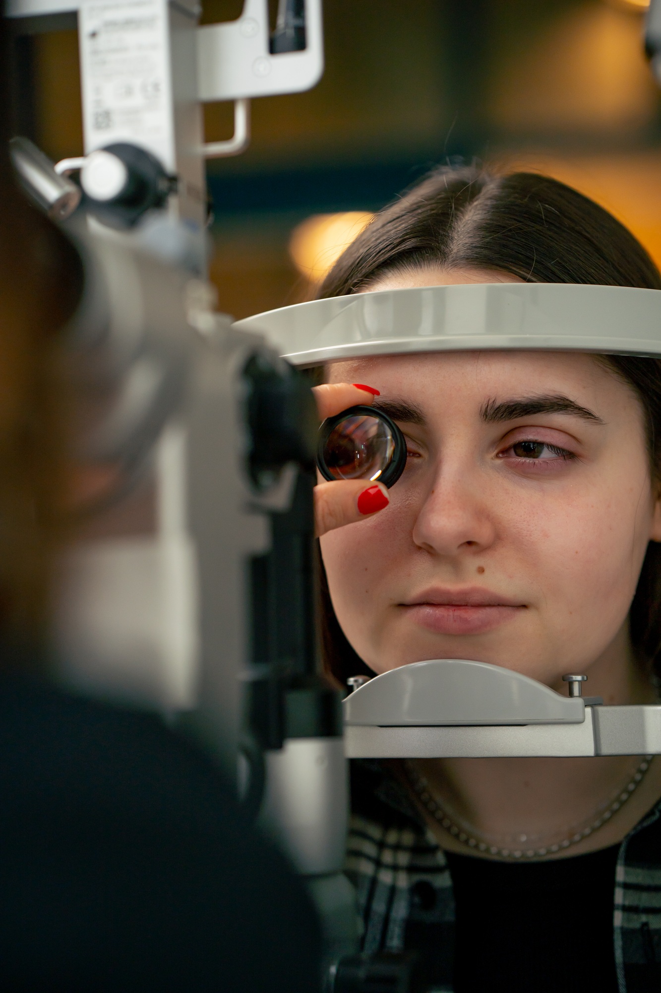in an ophthalmology clinic young doctor diagnoses a young girl with a magnifying lens